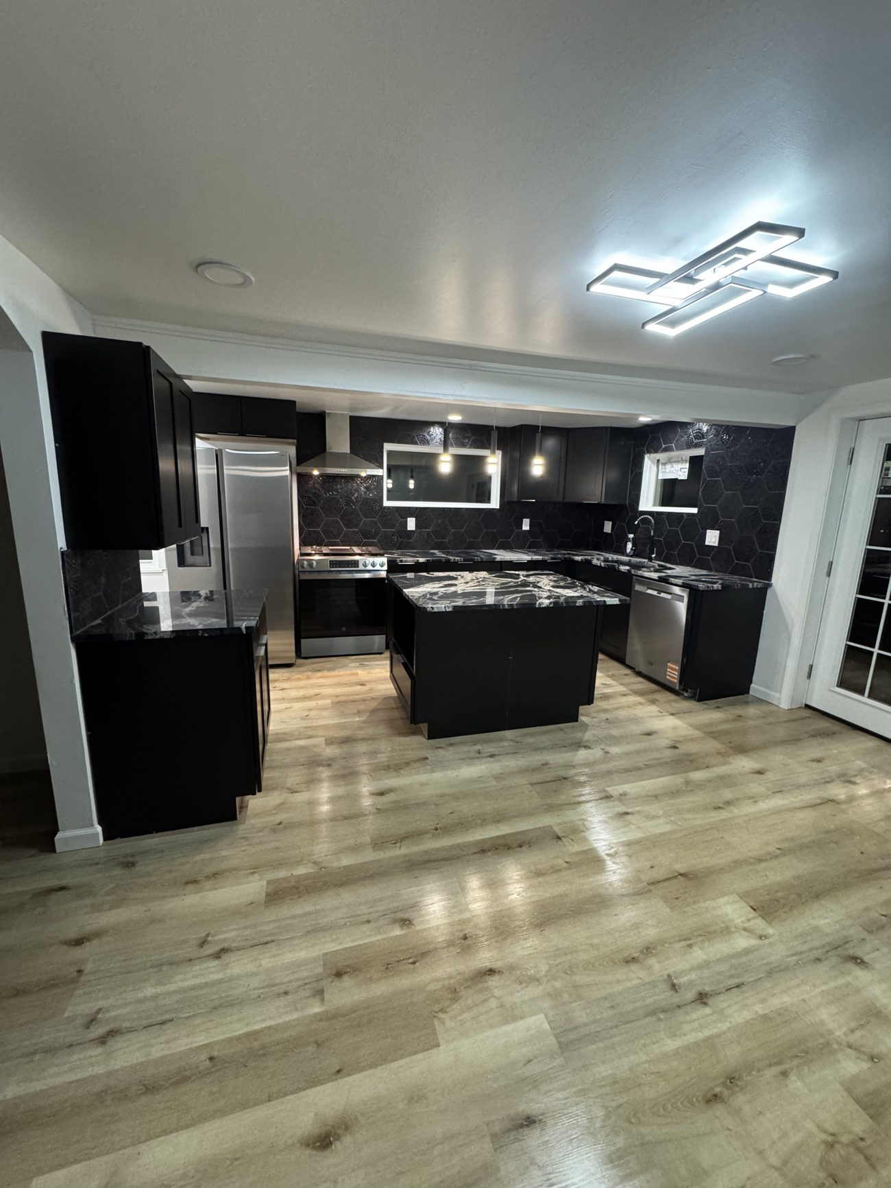 Modern kitchen remodel with black cabinets and waterfall marble island